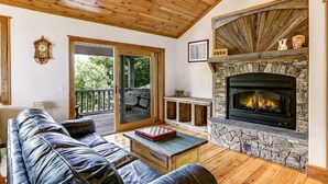A cozy living room with a stone fireplace, leather sofa, and a wooden ceiling. - Sunrise to Sunset (Hayesville)