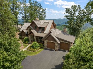 A large, multi-story house with a stone facade, multiple garage doors, and a driveway. - Sweet Autumn at Blue Ridge Mountain (Boone)