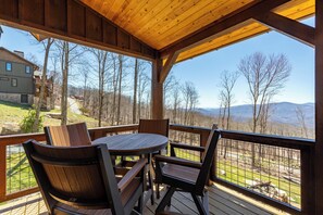A wooden deck with a table and chairs, overlooking a mountainous landscape. - SkyFall at Eagles Nest (Boone)