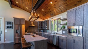 A modern kitchen with dark wood cabinets, stainless steel appliances, and a central island with bar stools. - Sweet Sejour (Deep Gap)
