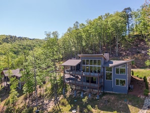 A modern two-story house with large windows, a deck, and a hillside setting. - Sweet Sejour (Deep Gap)