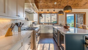 A modern kitchen with a large island, wooden ceiling, and a view of the outdoors. - Up and Away at Eagles Nest (Banner Elk)