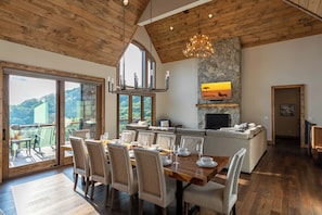 Un'ampia sala da pranzo con tavolo e sedie in legno, un camino in pietra e una grande finestra con vista panoramica.