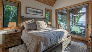 A bedroom with a large bed, wooden headboard, and a view of an outdoor patio with a table and chairs. - Up and Away at Eagles Nest (Banner Elk)