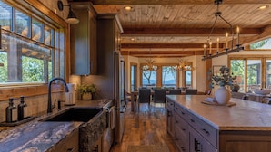 A spacious kitchen with a large island, wooden cabinets, and a stone countertop. - Almost Heaven at Eagles Nest (Banner Elk)