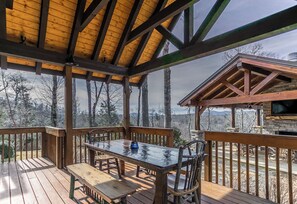A wooden deck with a table and chairs, overlooking a forested area. - Elk Camp Lodge (Newland)