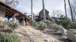 Un chalet rustique à la façade en pierre, avec des poutres en bois et un balcon donnant sur un paysage rocheux.