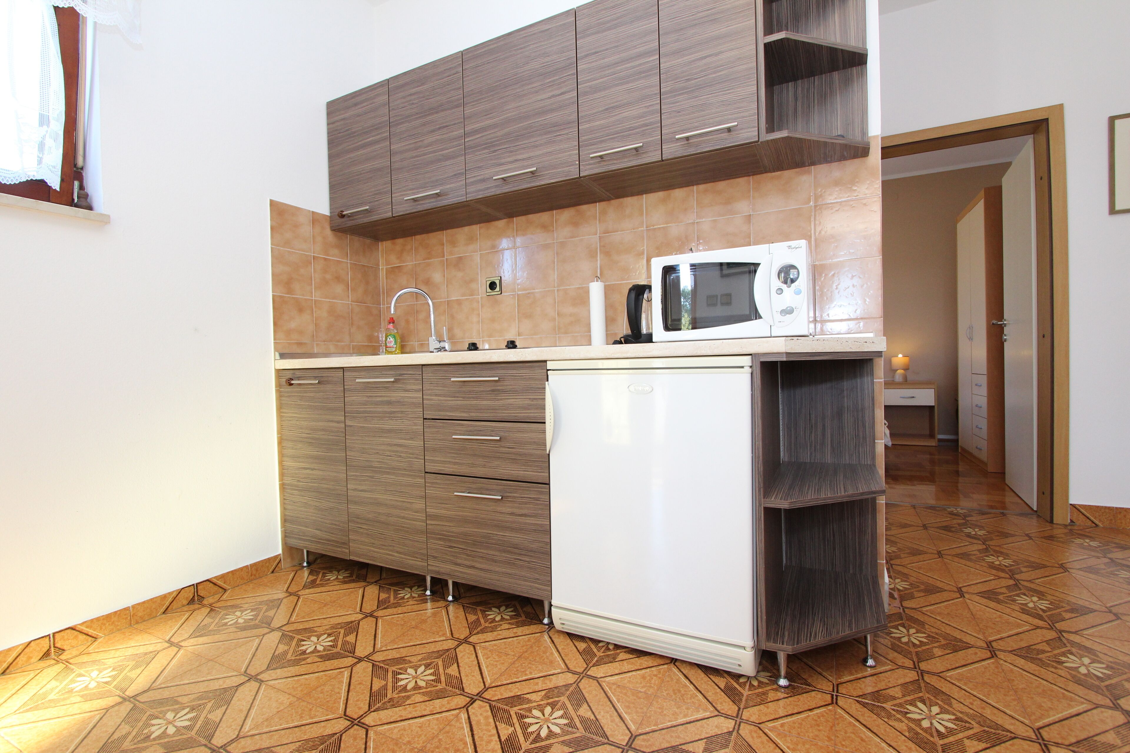 Una cocina con microondas, pileta y muebles de madera.