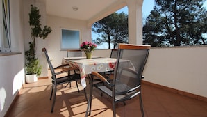 Une terrasse avec une table et des chaises, un pot de fleurs et une vue sur les arbres.
