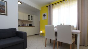 Un espace de vie compact comprenant un canapé, une table à manger, des chaises et un coin cuisine.