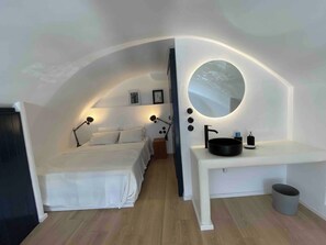 Un dormitorio con cama, lámparas de noche, un espejo y un lavamanos.