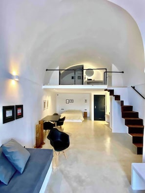 Un intérieur moderne avec une chambre en mezzanine, un coin repas et un escalier.