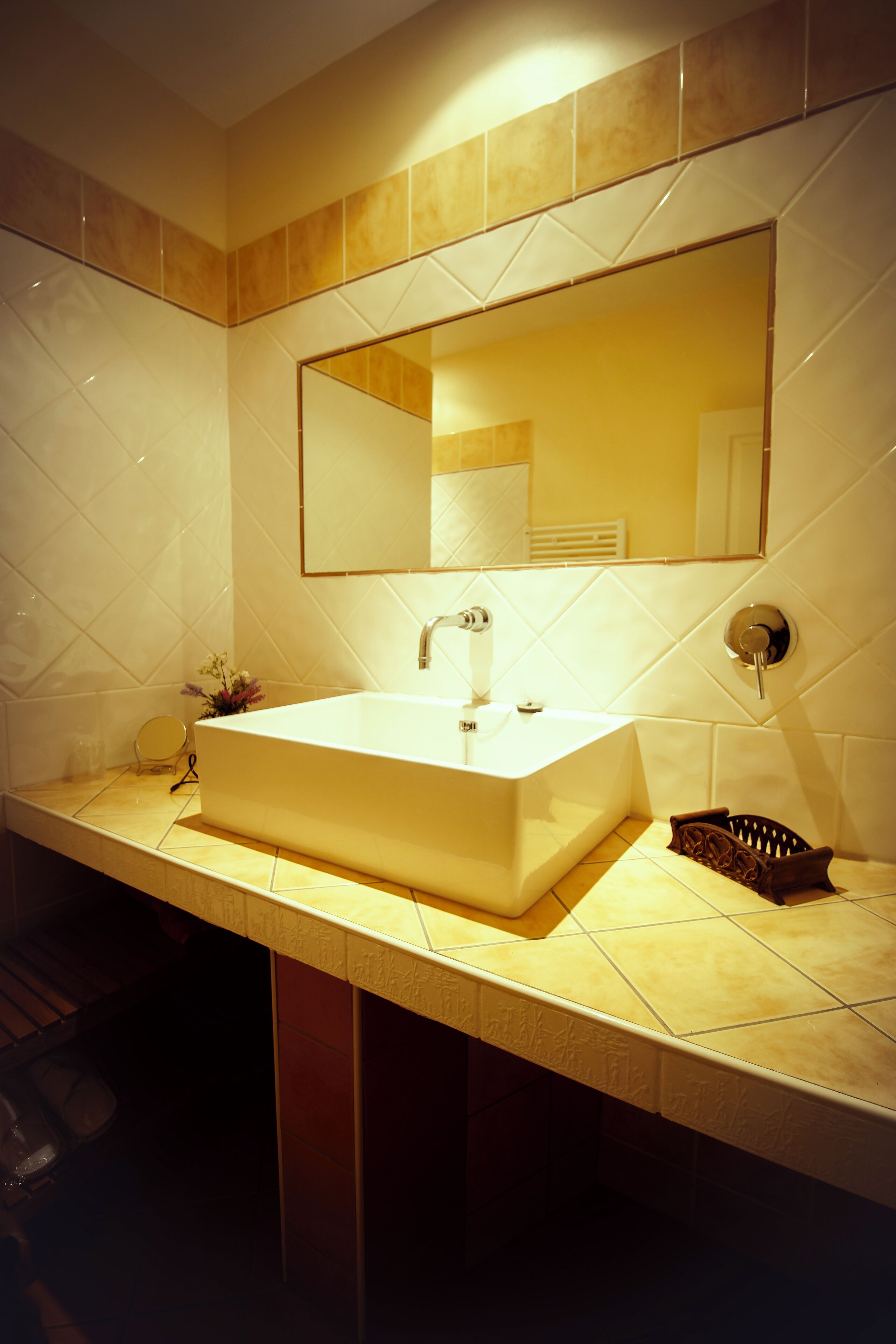 Un baño con un lavamanos grande y rectangular, un espejo encima y un perchero a la derecha.