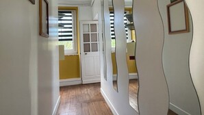 A hallway with wooden flooring, a white door, and a window with blinds. - Bâtisse du Xixe, Ranville (Ranville)
