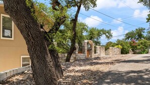 Zona residencial con un portón de piedra, árboles y un camino pavimentado.