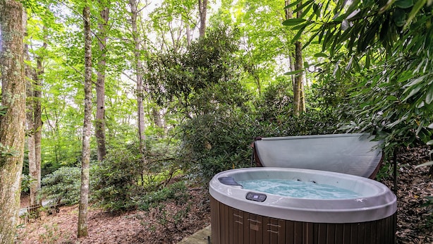 A hot tub in a forested area with a wooden deck. - Altitudes Attitude (Blowing Rock)