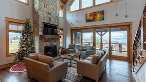 A spacious living room with a stone fireplace, leather sofas, and a Christmas tree. - Neverending Story at Eagles Nest (Elk Park)
