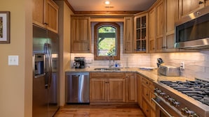 A kitchen with wooden cabinets, stainless steel appliances, a window, and a stone countertop. - Crystal Mountain Lodge (Boone)