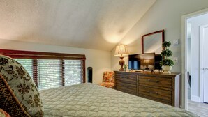 A bedroom with a bed, a dresser, a television, and a window with blinds. - Top Of Seven (Banner Elk)