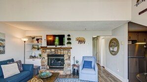 A living room with a stone fireplace, a blue sofa, a coffee table, and a blue armchair. - Top Of Seven (Banner Elk)