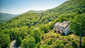 A house surrounded by dense forest, with a road curving through the landscape. - Top Of Seven (Banner Elk)