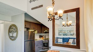 A modern kitchen with stainless steel appliances, a dining area with a glass table, and a large mirror reflecting the room. - Top Of Seven (Banner Elk)