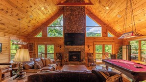 A log cabin interior with a fireplace, pool table, leather seating, and large windows. - Azalea Hill (Boone)