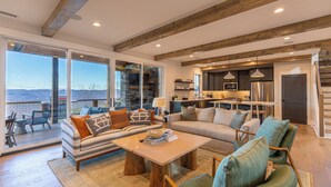 A spacious living area with a sofa, coffee table, and chairs, a kitchen with modern appliances, and a large sliding glass door leading to an outdoor deck. - The Overlook at Blue Ridge Mountain (Boone)