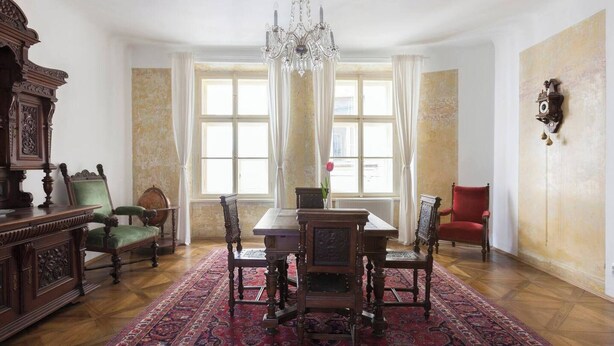 A traditional dining room with a wooden table, chairs, and a chandelier. - Antique Old Town Apartment (Prague)