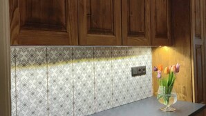 A kitchen with wooden cabinets, a patterned backsplash, and a glass vase with tulips on the countertop. - Antique Old Town Apartment (Prague)