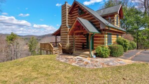 Une cabane en rondins avec des fondations en pierre, une véranda et une vue sur le paysage environnant.