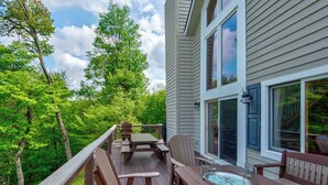 A deck with wooden furniture, a hot tub, and a glass enclosure. - Sunrise with Grandfather (Banner Elk)