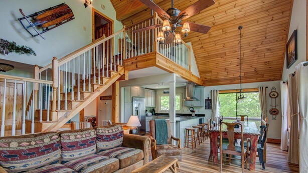A spacious living area with a wooden staircase, a kitchen, and a dining area. - Sunrise with Grandfather (Banner Elk)