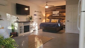 Een slaapkamer met een bed, nachtkastje, lamp en een tv aan de muur.