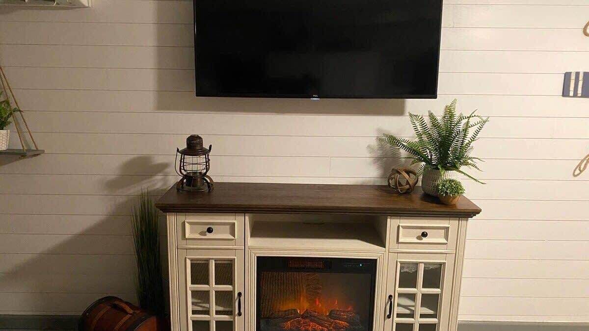 A fireplace with a TV mounted above it, a decorative plant, and a small shelf with a lantern.