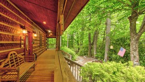 A wooden cabin with a porch, benches, and a view of a forested area. - Hebron Falls (Boone)