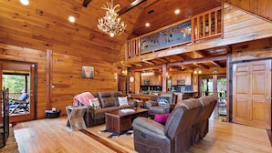 A spacious wooden cabin with a living area featuring leather sofas, a dining table, and a kitchen in the background. - Come to Escape (Marion)