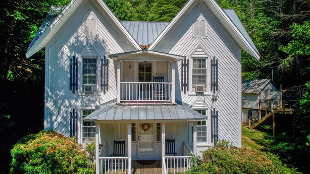 Une maison à deux étages avec un porche à l’avant, un balcon et une cheminée.