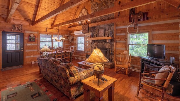 A log cabin interior with a fireplace, wooden furniture, and a television. - Altitude Adjustment (Banner Elk)