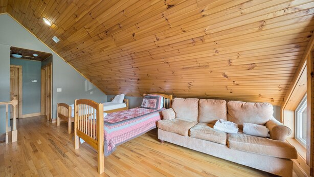 Ein gemütliches Zimmer mit Holzbalkendecke, einer Couch, einem Bett mit kariertem Überwurf und einem Fenster.