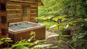 A wooden cabin with a hot tub and a lush garden. - Hidden Creek Cabin (Fleetwood)