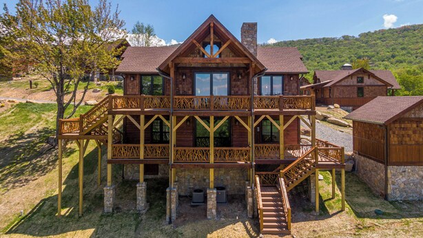 A wooden cabin with a balcony, stone foundation, and a stone chimney. - Kikis Hideaway at Eagles Nest (Banner Elk)