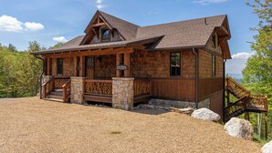 A lodge with a stone foundation, wooden exterior, and a staircase leading to the entrance. - Kikis Hideaway at Eagles Nest (Banner Elk)