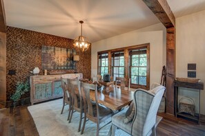 Un coin repas rustique avec une table en bois, des chaises et un lustre.