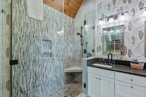 Une salle de bain moderne avec une douche à parois de verre, un meuble-lavabo blanc avec un miroir et un mur décoré d’un motif.
