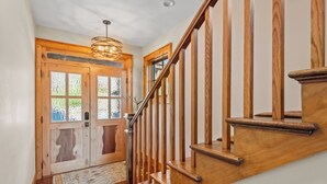 Una escalera de madera con puerta de vidrio y una lámpara colgante.