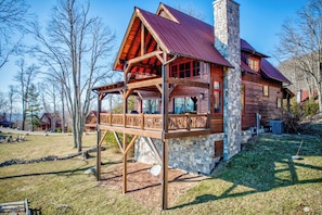 Une cabane en rondins avec une cheminée en pierre, un balcon en bois et des fondations en pierre.