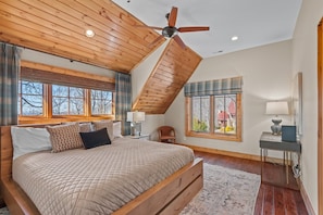 Une chambre avec un grand lit, un plafond en bois et une vue sur l’extérieur.
