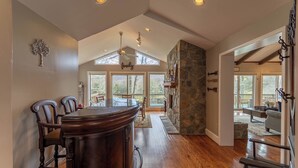 A spacious kitchen with a large island, stone fireplace, and a dining area with chairs. - Emerald Escape (Banner Elk)