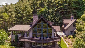 A large, two-story cabin with a wrap-around porch, surrounded by dense forest. - Mountaineer Manor (Sugar Grove)